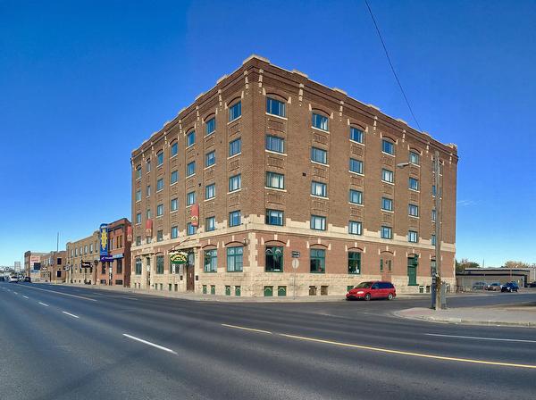 Old heritage brick building in Regina Warehouse district on the corner with blue sky and road 