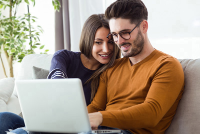 A couple of home buyers reviewing listings on their computer 