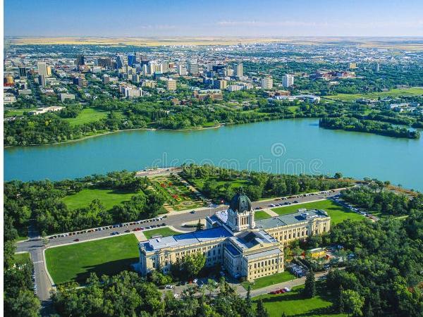 Ariel picture of Wascana Lake and the parliament building in Regina in summer blue water and green trees with Regina in the back